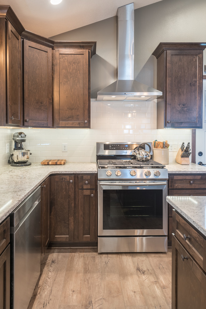 Example of a large mountain style u-shaped dark wood floor and brown floor enclosed kitchen design in Minneapolis with a double-bowl sink, shaker cabinets, dark wood cabinets, granite countertops, white backsplash, subway tile backsplash, stainless steel appliances and an island