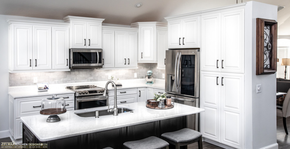 Foto på ett mellanstort vintage vit kök, med en undermonterad diskho, luckor med upphöjd panel, vita skåp, bänkskiva i kvarts, vitt stänkskydd, stänkskydd i keramik, klinkergolv i porslin, en köksö och brunt golv
