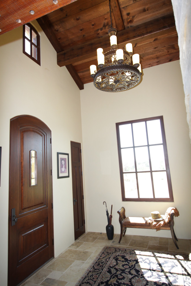 Cette photo montre une porte d'entrée méditerranéenne de taille moyenne avec une porte simple, une porte en bois foncé, un mur beige, un sol en travertin, un sol multicolore et un plafond en bois.