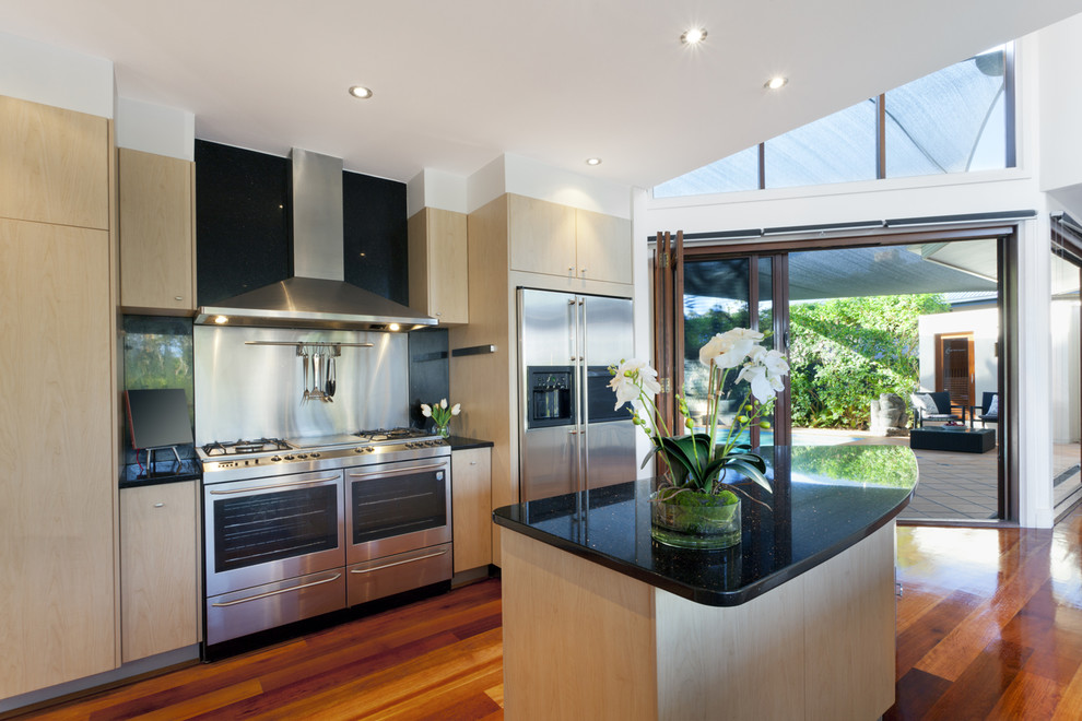 Photo of a mid-sized contemporary single-wall separate kitchen in Sydney with an integrated sink, flat-panel cabinets, light wood cabinets, quartz benchtops, metallic splashback, metal splashback, stainless steel appliances, light hardwood floors, with island and brown floor.