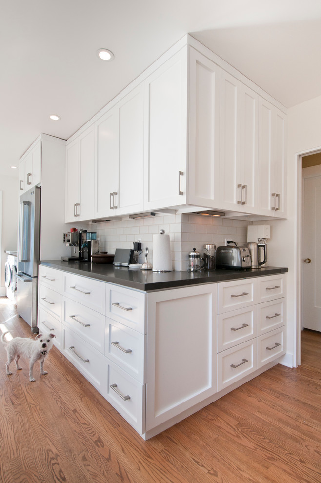 Inspiration for a mid-sized transitional l-shaped kitchen pantry in Los Angeles with an undermount sink, shaker cabinets, white cabinets, quartz benchtops, grey splashback, subway tile splashback, stainless steel appliances, medium hardwood floors and no island.
