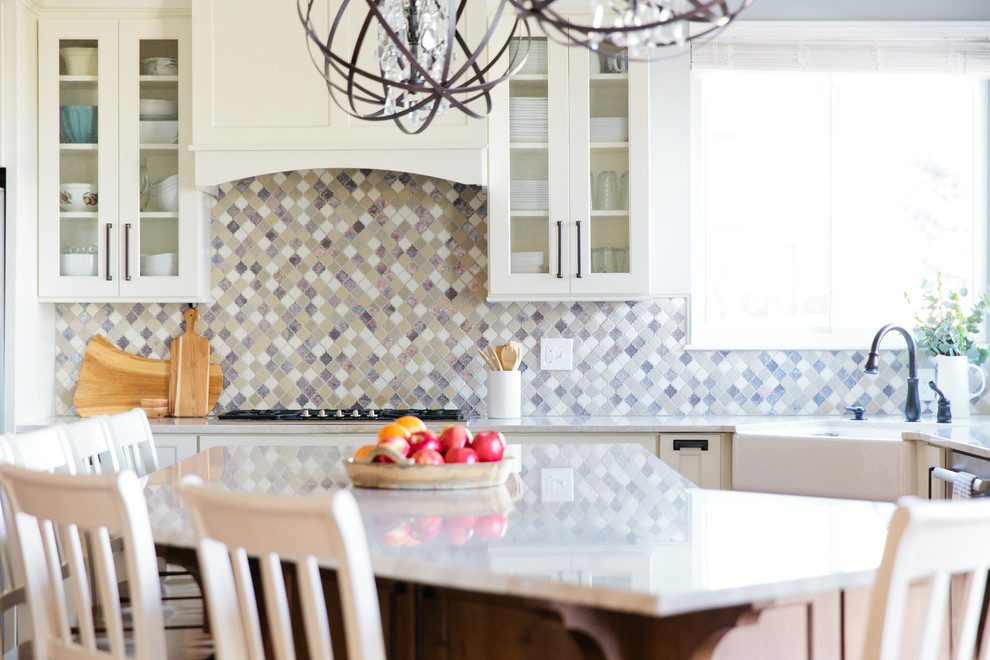 Example of a large transitional u-shaped light wood floor eat-in kitchen design in Denver with a farmhouse sink, shaker cabinets, white cabinets, quartz countertops, multicolored backsplash, porcelain backsplash, stainless steel appliances and an island