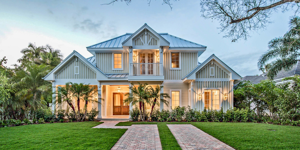 Expansive tropical two-storey grey house exterior in Miami with wood siding, a hip roof and a metal roof.