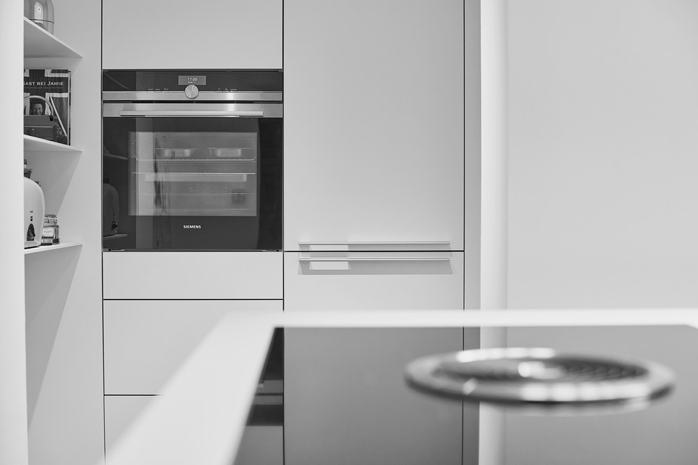 Immagine di un cucina con isola centrale design chiuso con lavello da incasso, ante bianche e pavimento grigio