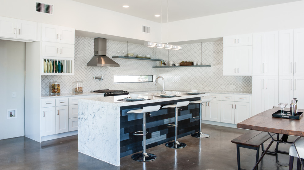 Example of a large minimalist l-shaped concrete floor open concept kitchen design in Austin with an undermount sink, shaker cabinets, white cabinets, marble countertops, white backsplash, ceramic backsplash, stainless steel appliances and an island