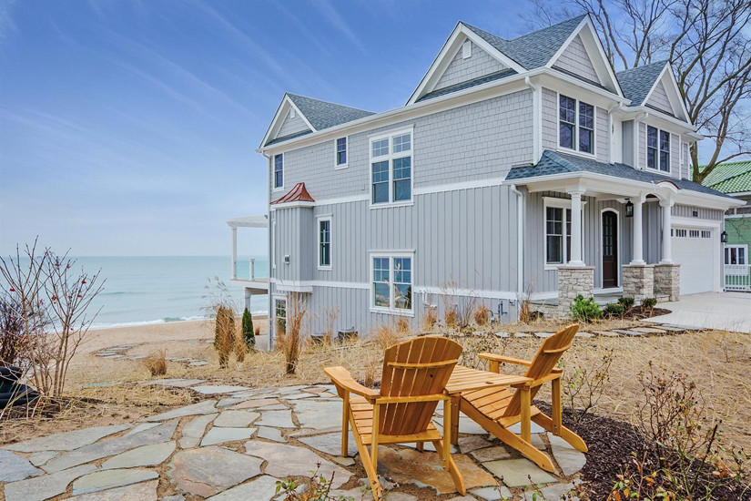 This is an example of an expansive beach style three-storey grey house exterior in Chicago with wood siding, a gable roof and a shingle roof.