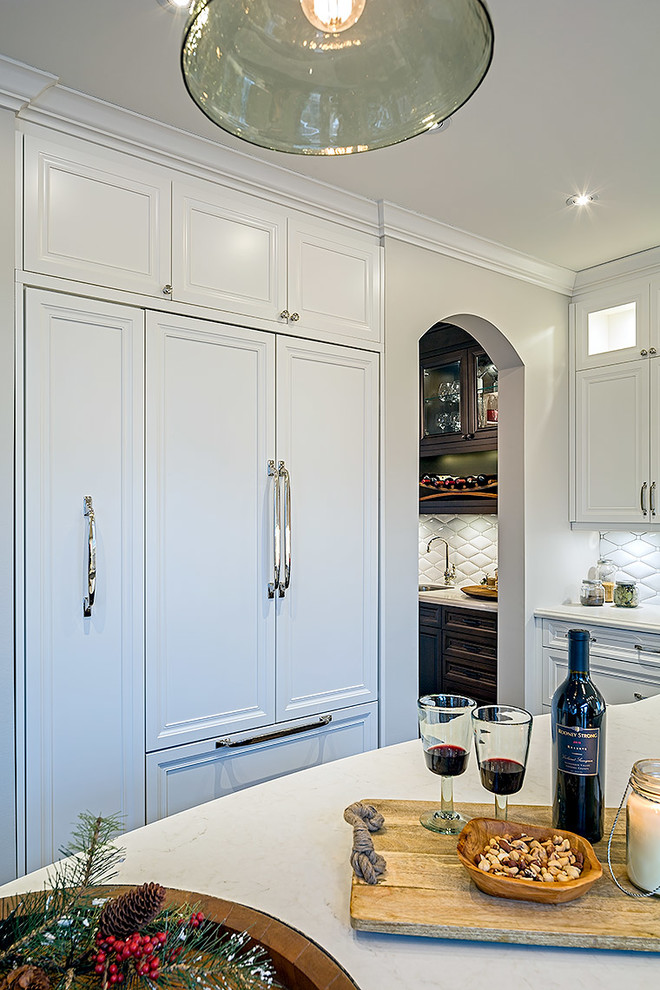 Enclosed kitchen - mid-sized transitional l-shaped enclosed kitchen idea in Toronto with white cabinets, quartz countertops and an island