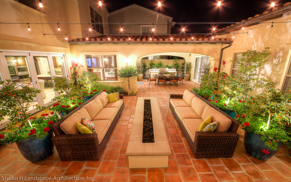 Photo of a mid-sized mediterranean courtyard patio in Orange County with a fire feature and concrete pavers.