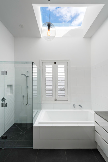 This is an example of a small contemporary kids bathroom in Melbourne with white cabinets, a corner shower, gray tile, porcelain tile, white walls and ceramic floors.
