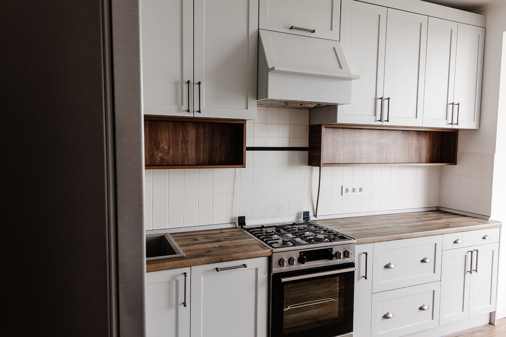 Mid-sized transitional u-shaped dark wood floor and brown floor eat-in kitchen photo in DC Metro with a drop-in sink, recessed-panel cabinets, white cabinets, wood countertops, white backsplash, ceramic backsplash, stainless steel appliances, a peninsula and brown countertops