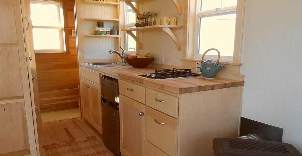 Photo of a small traditional galley kitchen in Portland with a farmhouse sink, flat-panel cabinets, light wood cabinets, wood benchtops and light hardwood floors.