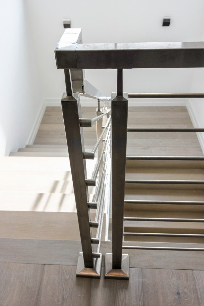 Inspiration pour un escalier flottant minimaliste de taille moyenne avec des marches en bois, des contremarches en bois, un garde-corps en métal et du lambris de bois.