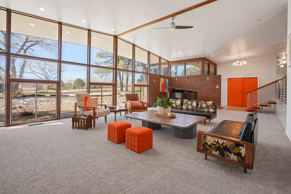 Photo of an expansive midcentury formal open concept living room in Albuquerque with white walls, carpet, a standard fireplace, a concrete fireplace surround and beige floor.