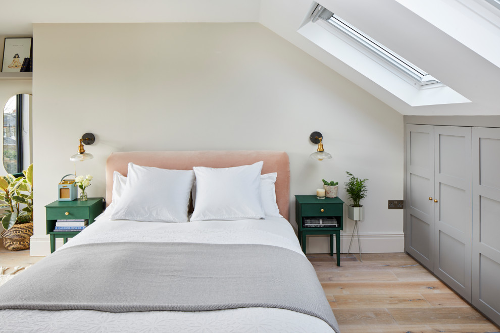 Photo of a mid-sized transitional bedroom in London with white walls, light hardwood floors and beige floor.