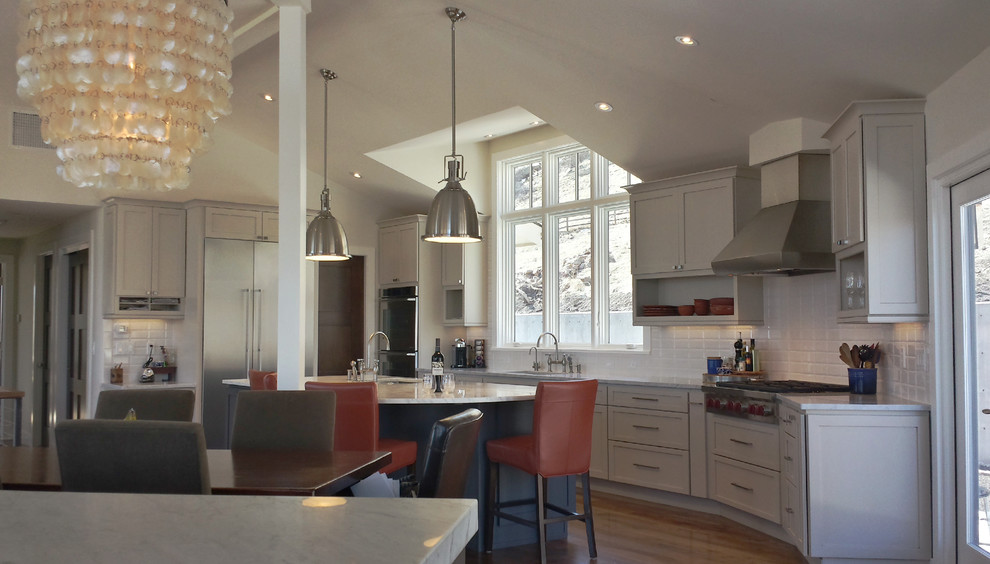 Inspiration for a large medium tone wood floor kitchen remodel in Denver with a single-bowl sink, shaker cabinets, white cabinets, quartz countertops, white backsplash, ceramic backsplash, stainless steel appliances and an island