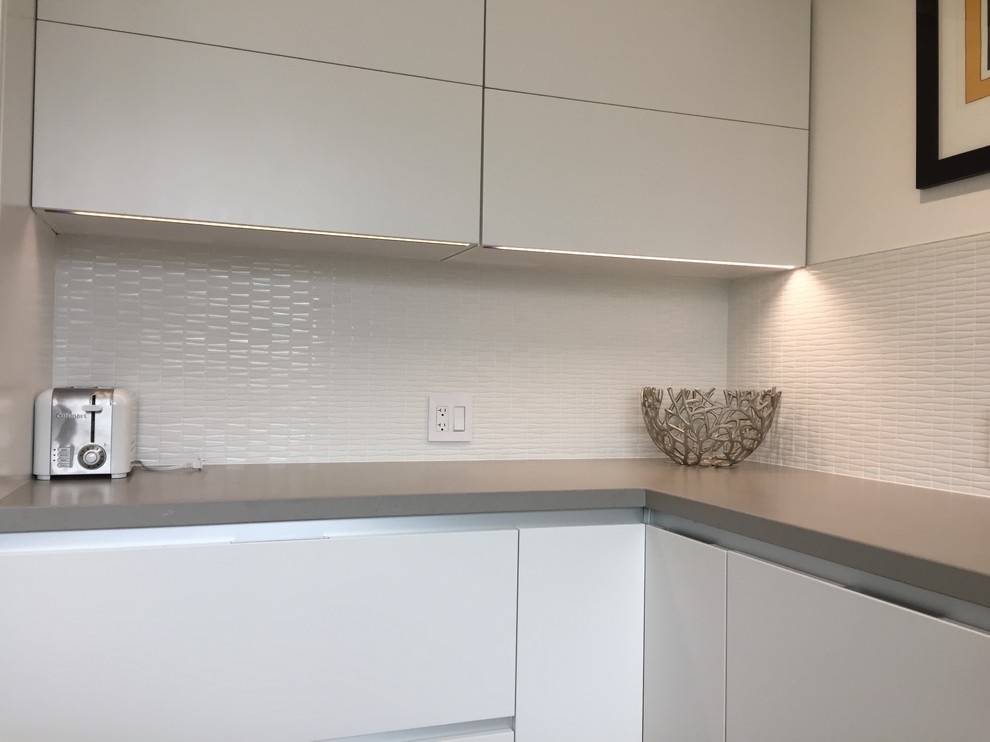 Design ideas for a mid-sized modern u-shaped separate kitchen in Toronto with flat-panel cabinets, white cabinets, white splashback, stainless steel appliances, with island, matchstick tile splashback, an undermount sink, quartz benchtops, concrete floors, grey floor and white benchtop.