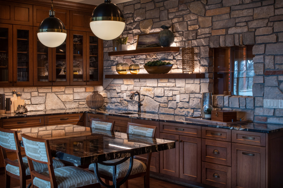 Inspiration for a large traditional l-shaped wet bar in Minneapolis with an undermount sink, recessed-panel cabinets, dark wood cabinets, grey splashback, limestone splashback, dark hardwood floors, brown floor and black benchtop.