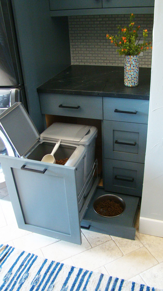 This is an example of a large transitional u-shaped utility room in Denver with shaker cabinets, blue cabinets, granite benchtops, white walls, travertine floors, a stacked washer and dryer, multi-coloured floor and black benchtop.