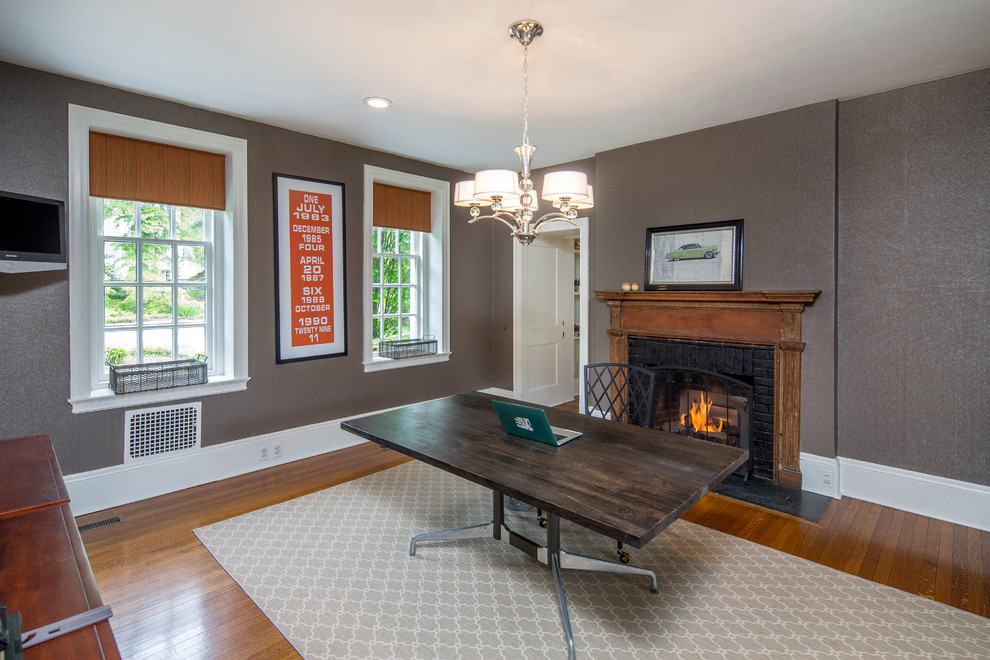 This is an example of a traditional study room in Philadelphia with grey walls, medium hardwood floors, a standard fireplace and a brick fireplace surround.