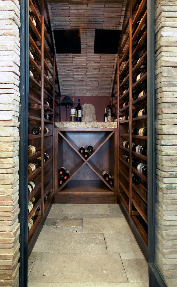 Small mediterranean wine cellar in Orange County with limestone floors and storage racks.