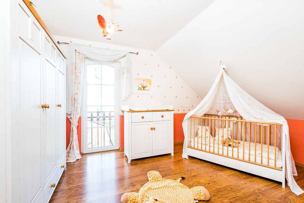 Design ideas for a mid-sized traditional nursery for girls in Other with red walls, painted wood floors and brown floor.