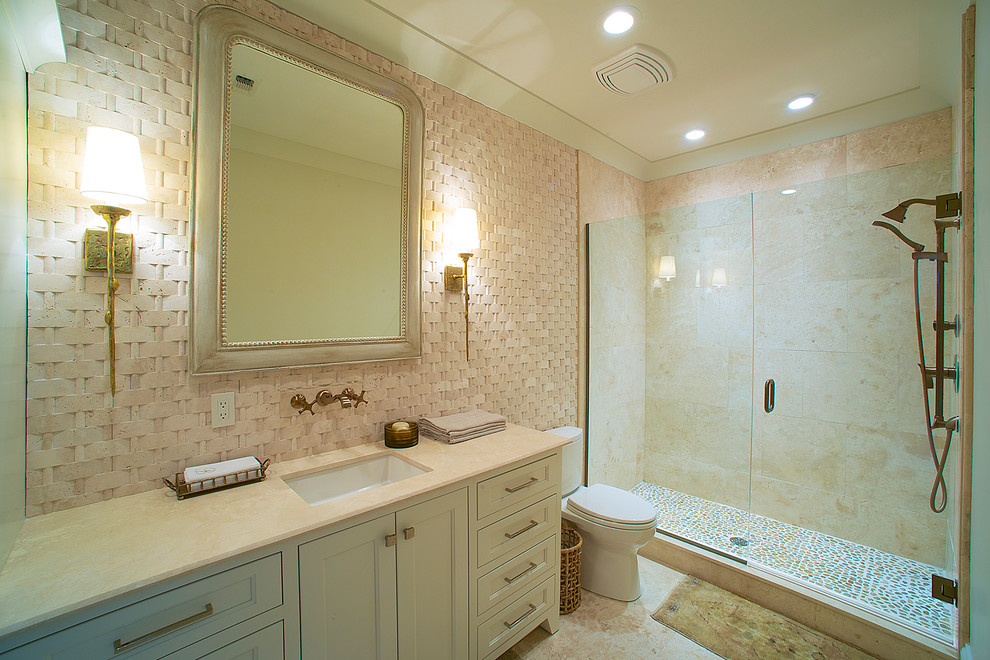 This is an example of a medium sized traditional shower room bathroom in Miami with beaded cabinets, white cabinets, an alcove shower, a two-piece toilet, beige tiles, ceramic tiles, beige walls, travertine flooring, a submerged sink, beige floors, a hinged door and beige worktops.