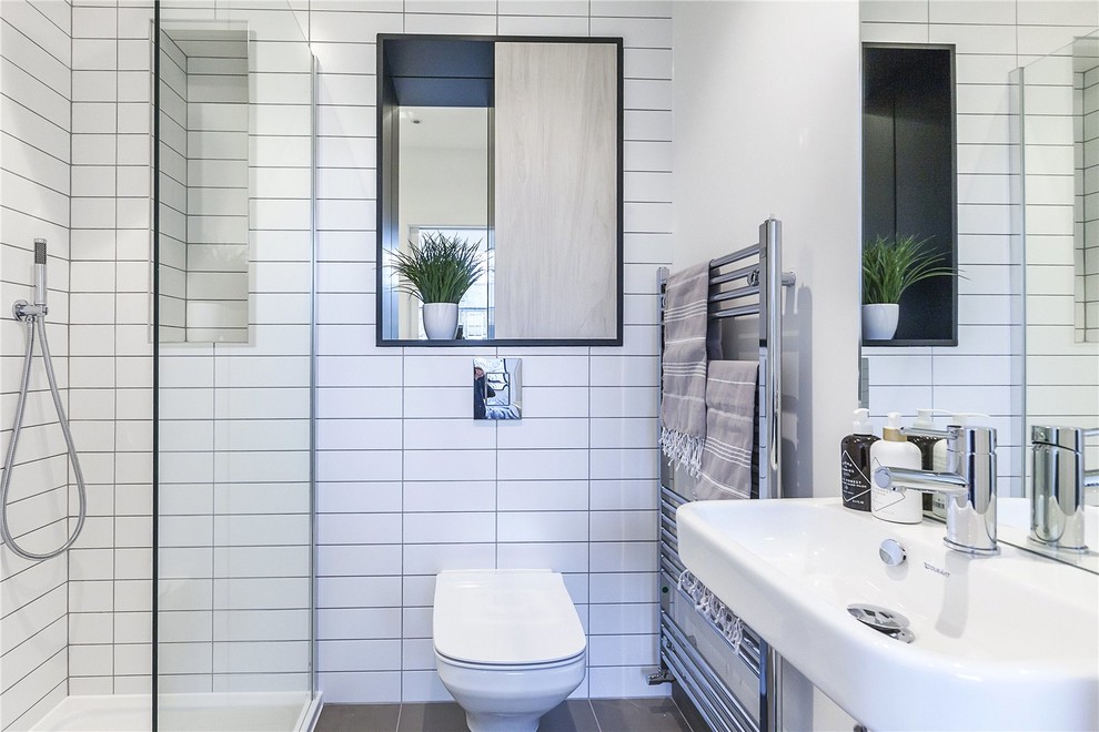 Inspiration for a mid-sized contemporary master bathroom in London with recessed-panel cabinets, medium wood cabinets, a drop-in tub, a curbless shower, a wall-mount toilet, gray tile, ceramic tile, white walls, ceramic floors, a wall-mount sink, tile benchtops, grey floor, an open shower and white benchtops.