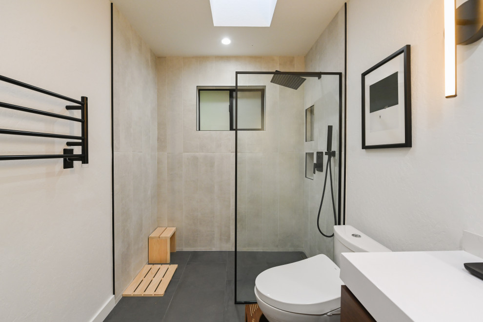 На фото: маленькая ванная комната в современном стиле с плоскими фасадами, фасадами цвета дерева среднего тона, душем в нише, унитазом-моноблоком, серой плиткой, керамической плиткой, бежевыми стенами, полом из керамической плитки, душевой кабиной, мраморной столешницей, серым полом, душем с распашными дверями, белой столешницей, нишей, тумбой под одну раковину, подвесной тумбой и панелями на части стены для на участке и в саду