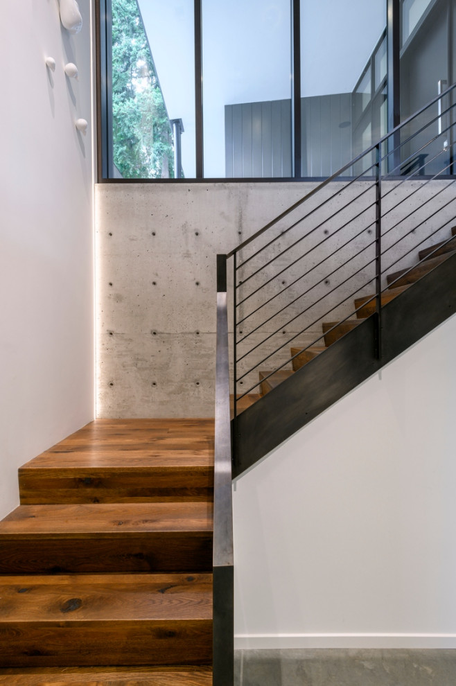 This is an example of a contemporary wood l-shaped staircase in Seattle with wood risers and cable railing.