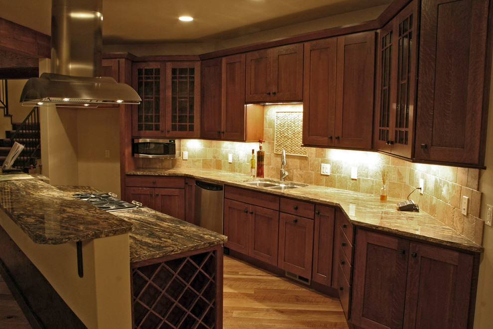 Eat-in kitchen - large rustic l-shaped medium tone wood floor and brown floor eat-in kitchen idea with a double-bowl sink, shaker cabinets, dark wood cabinets, granite countertops, beige backsplash, limestone backsplash, stainless steel appliances and an island