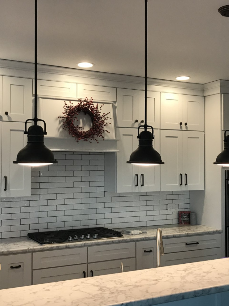 Photo of a mid-sized country single-wall eat-in kitchen in Denver with a farmhouse sink, shaker cabinets, white cabinets, laminate benchtops, white splashback, subway tile splashback, stainless steel appliances, with island and white benchtop.