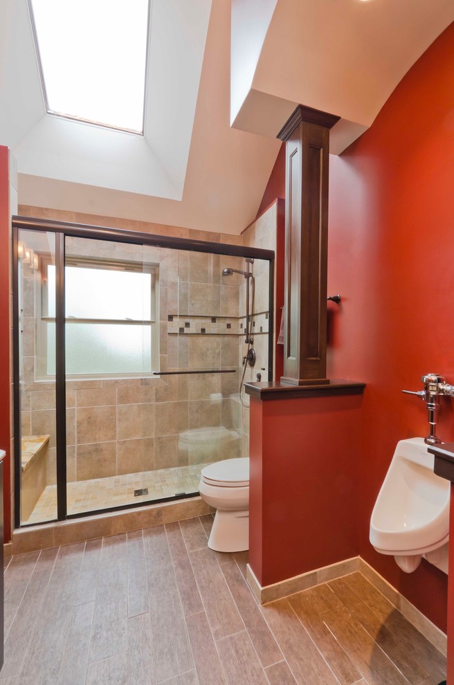 Photo of a mid-sized traditional kids bathroom in Chicago with an undermount sink, raised-panel cabinets, dark wood cabinets, marble benchtops, an alcove shower, an urinal, beige tile, porcelain tile, red walls and porcelain floors.