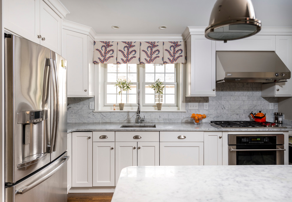 Photo of a large transitional l-shaped eat-in kitchen in Philadelphia with an undermount sink, shaker cabinets, white cabinets, stainless steel appliances, medium hardwood floors, with island and brown floor.