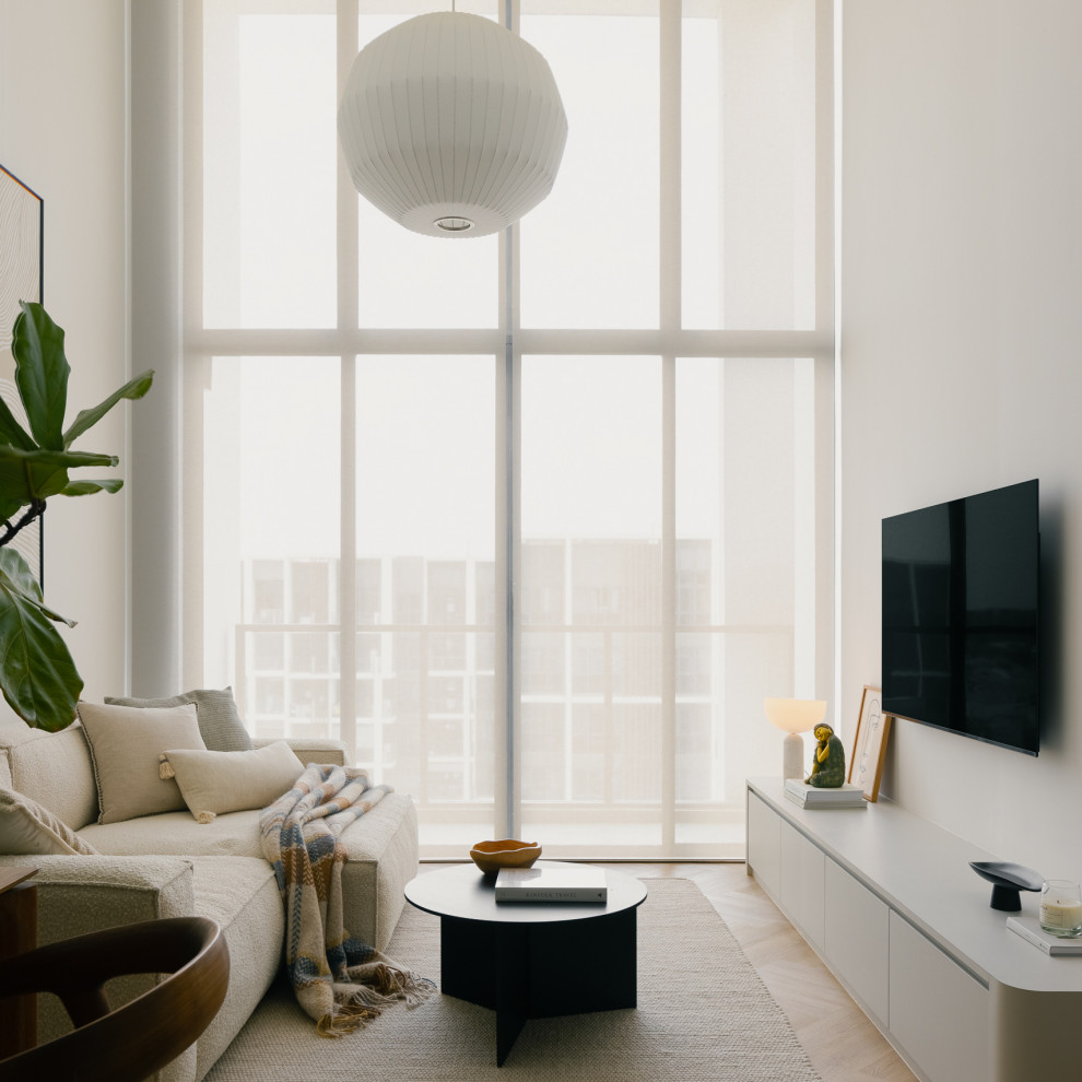 This is an example of a contemporary living room in Singapore With White Walls, Light Hardwood Floors and a Wall-mounted TV.