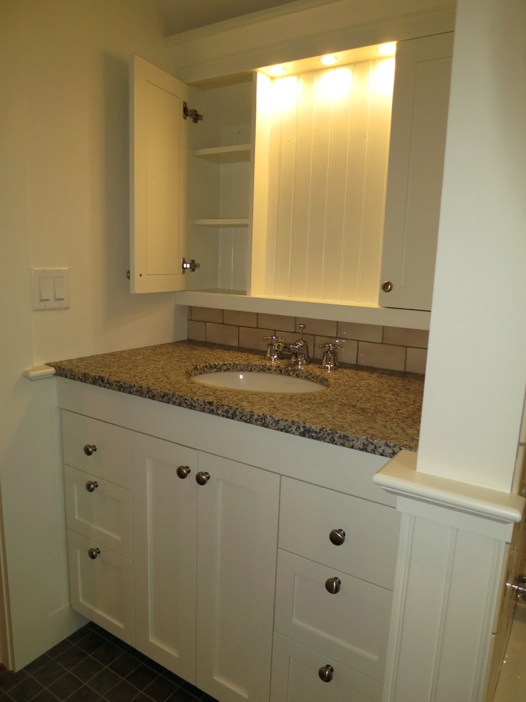 Photo of a small traditional bathroom in Other with an undermount sink, shaker cabinets, white cabinets, granite benchtops, beige tile, subway tile, white walls and ceramic floors.