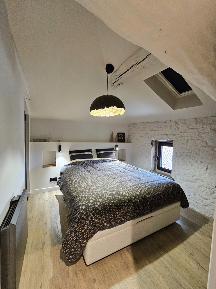 Design ideas for a mid-sized contemporary loft-style bedroom in Lyon with white walls, laminate floors and exposed beam.