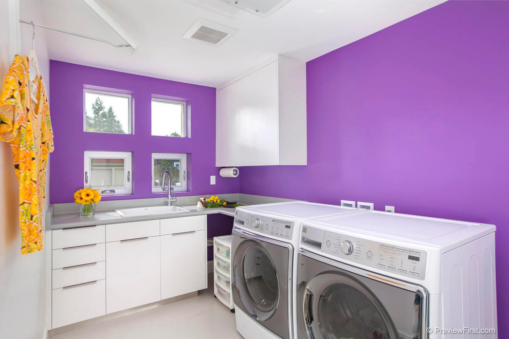 Photo of a large contemporary l-shaped dedicated laundry room in San Diego with a drop-in sink, flat-panel cabinets, white cabinets and purple walls.