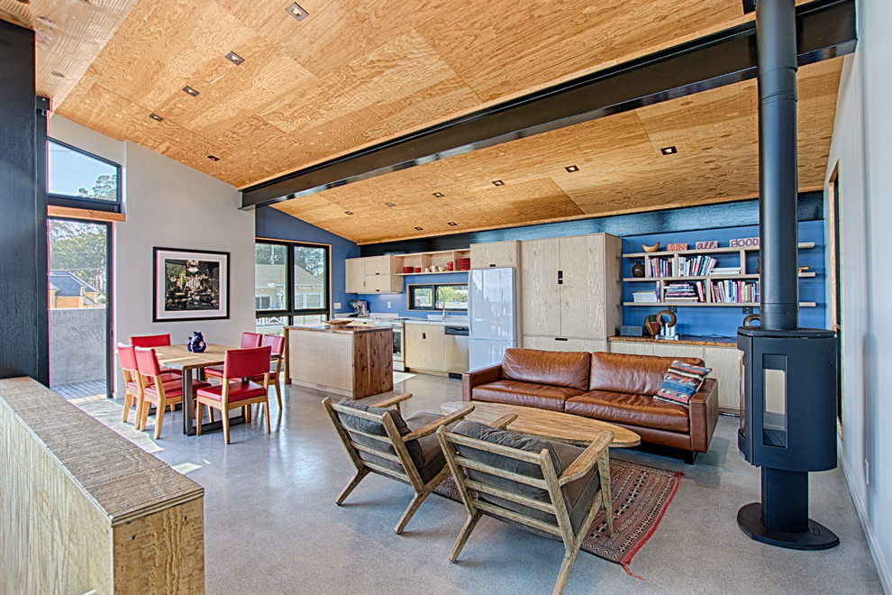 Small beach style open concept family room in San Francisco with blue walls, concrete floors, a wood stove, a metal fireplace surround, no tv and grey floor.