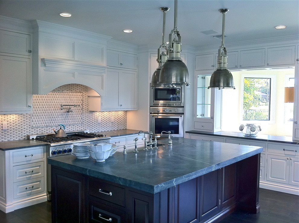 Open concept kitchen - large transitional u-shaped dark wood floor and brown floor open concept kitchen idea in Miami with a farmhouse sink, shaker cabinets, white cabinets, granite countertops, multicolored backsplash, stone tile backsplash, stainless steel appliances and an island