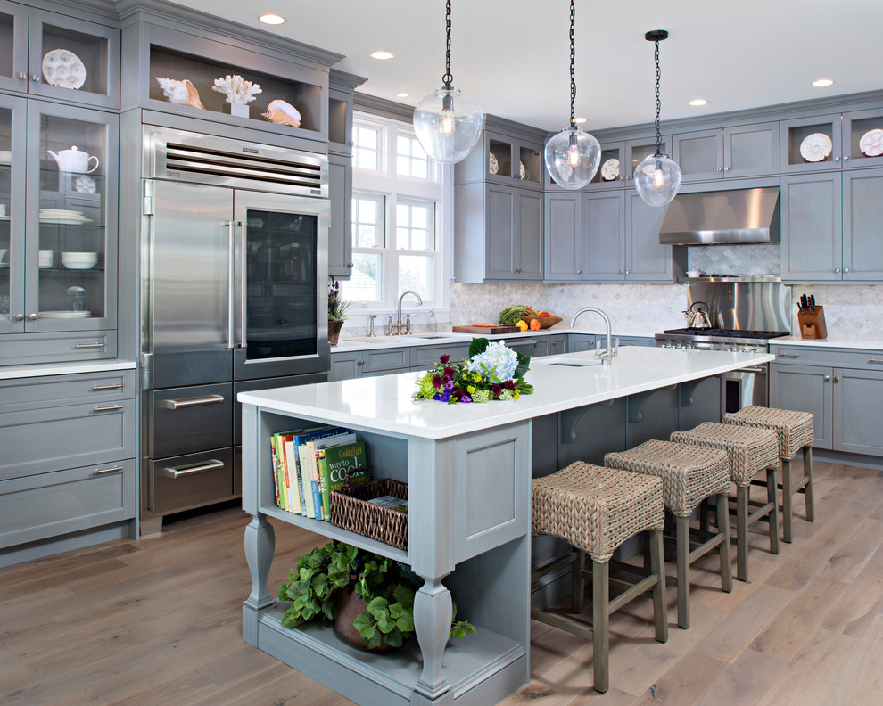 Example of a large transitional l-shaped medium tone wood floor open concept kitchen design with recessed-panel cabinets, gray cabinets, quartz countertops, gray backsplash, stainless steel appliances, an island, an undermount sink and porcelain backsplash