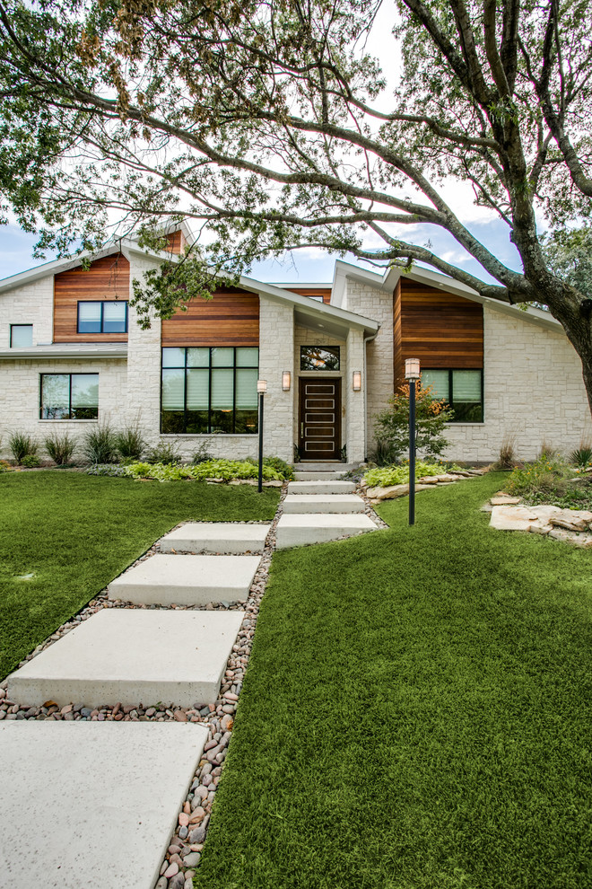 Photo of a mid-sized midcentury one-storey beige house exterior in Dallas with stone veneer and a shed roof.