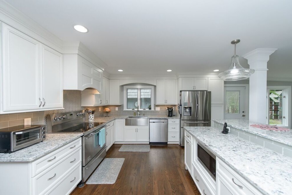 Inspiration for a transitional l-shaped medium tone wood floor eat-in kitchen remodel in Baltimore with a farmhouse sink, beaded inset cabinets, white cabinets, granite countertops, gray backsplash, glass tile backsplash, stainless steel appliances and an island
