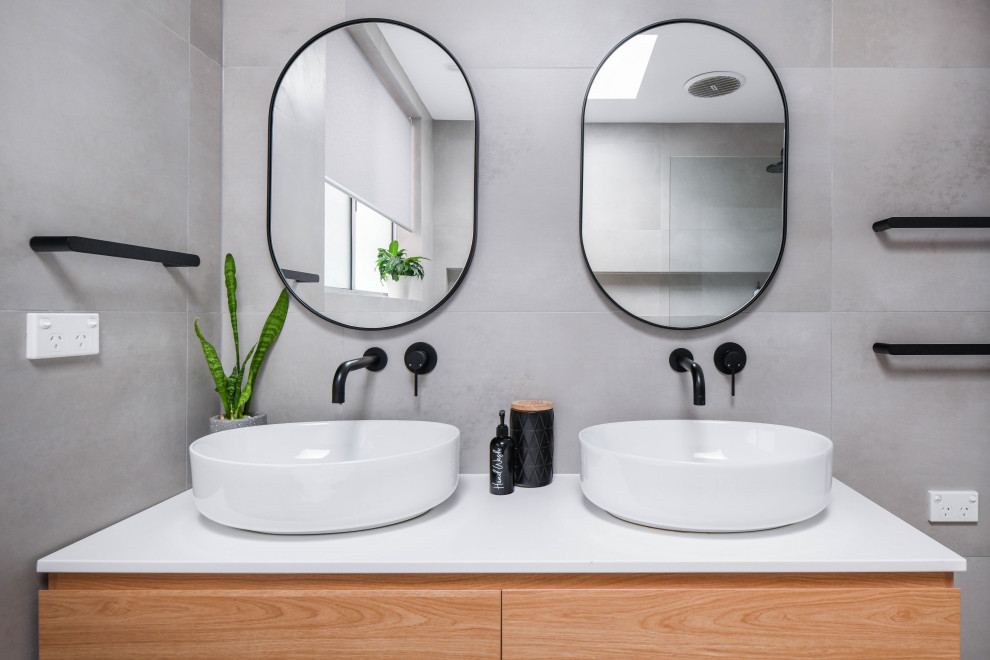 Photo of a mid-sized modern master bathroom in Sydney with flat-panel cabinets, brown cabinets, a freestanding tub, an open shower, a one-piece toilet, gray tile, ceramic tile, grey walls, ceramic floors, a drop-in sink, engineered quartz benchtops, grey floor, an open shower, yellow benchtops, a niche, a floating vanity and a double vanity.