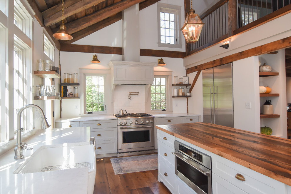 Inspiration for a mid-sized transitional u-shaped medium tone wood floor, brown floor and exposed beam kitchen pantry remodel in Other with a farmhouse sink, shaker cabinets, gray cabinets, wood countertops, white backsplash, subway tile backsplash, stainless steel appliances, an island and white countertops