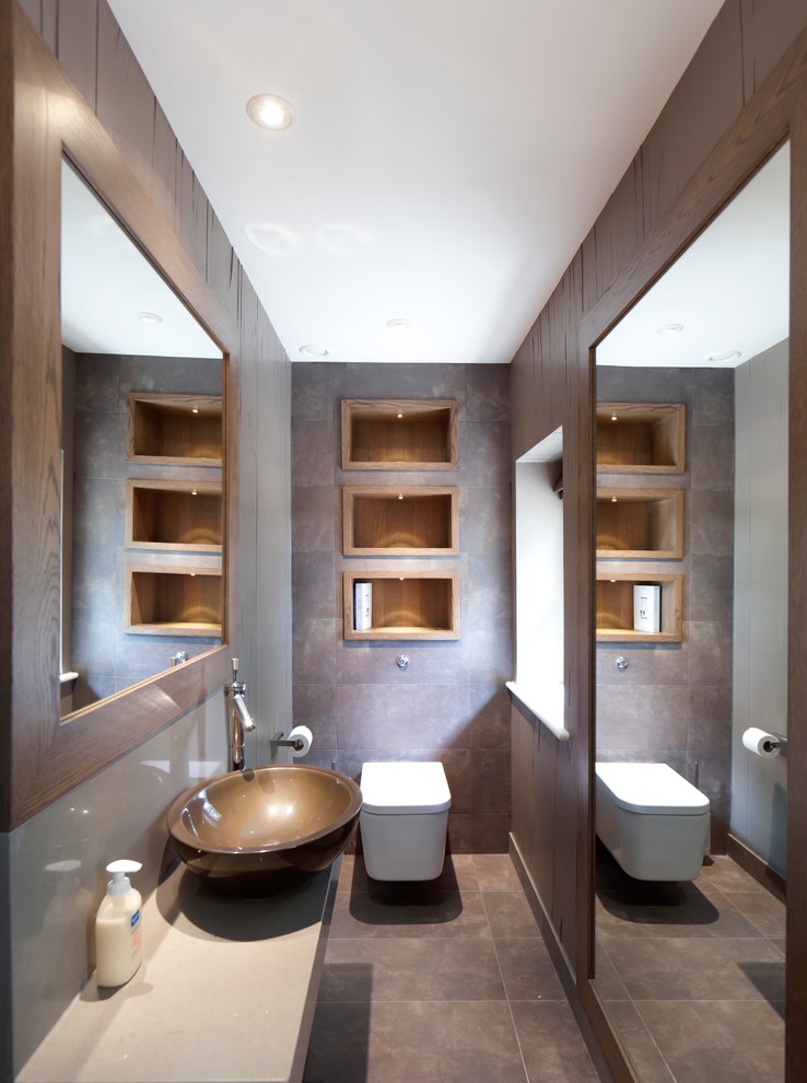 Design ideas for a contemporary powder room in Gloucestershire with a vessel sink, a wall-mount toilet and brown tile.