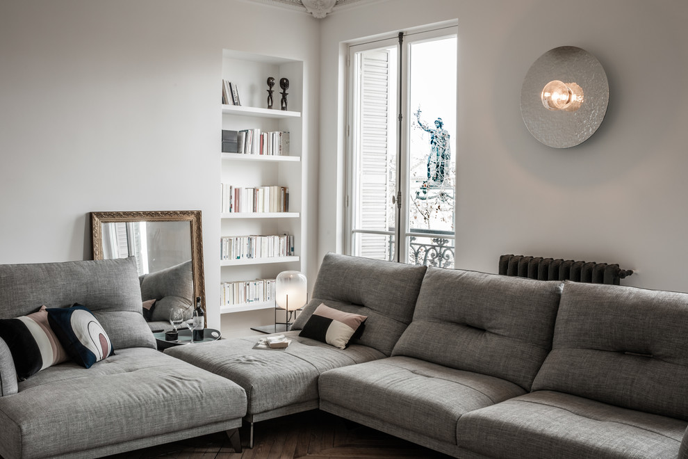 This is an example of an expansive contemporary open concept living room in Paris with a music area, white walls, light hardwood floors and a freestanding tv.
