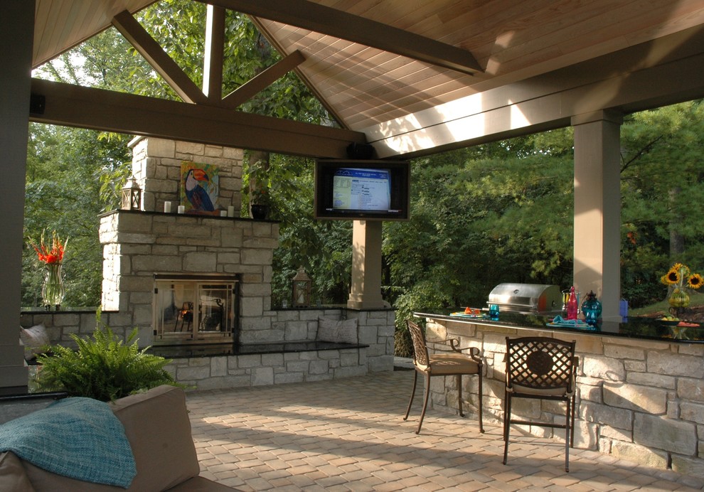 Photo of a large tropical backyard patio in Cincinnati with a fire feature, natural stone pavers and a gazebo/cabana.