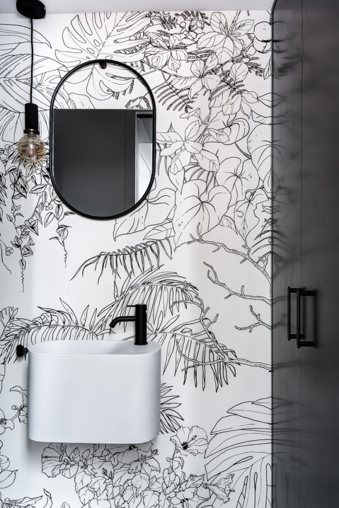 Photo of a small modern powder room in Paris with black cabinets, a wall-mount toilet, white walls, a wall-mount sink and wallpaper.