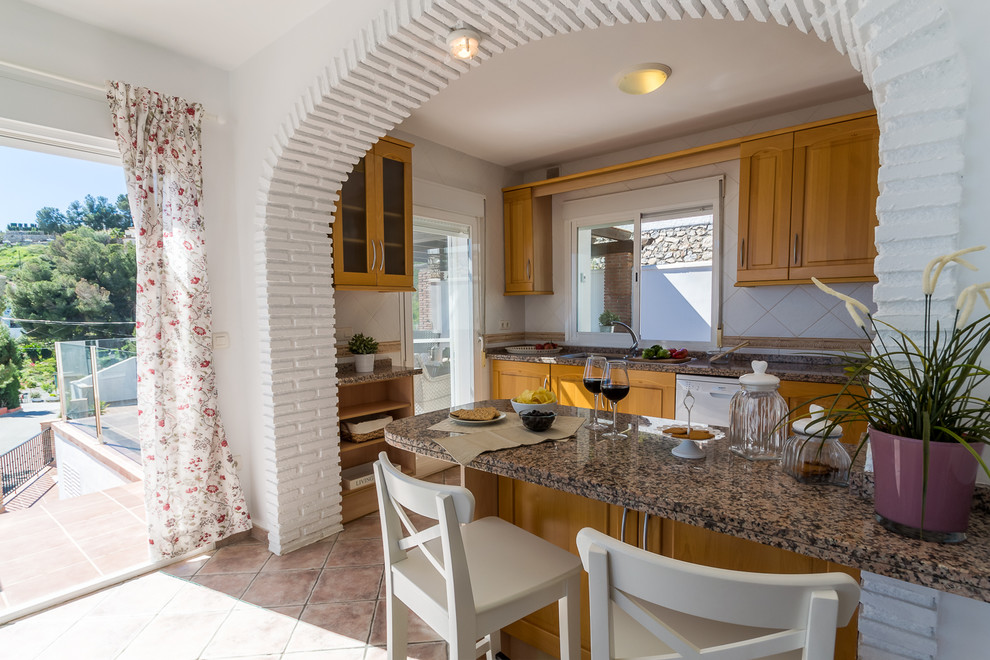 Diseño de cocinas en L mediterránea de tamaño medio abierta con fregadero de doble seno, armarios con paneles con relieve, puertas de armario beige, encimera de granito, salpicadero beige, salpicadero de azulejos de piedra, electrodomésticos blancos, suelo de baldosas de terracota y península