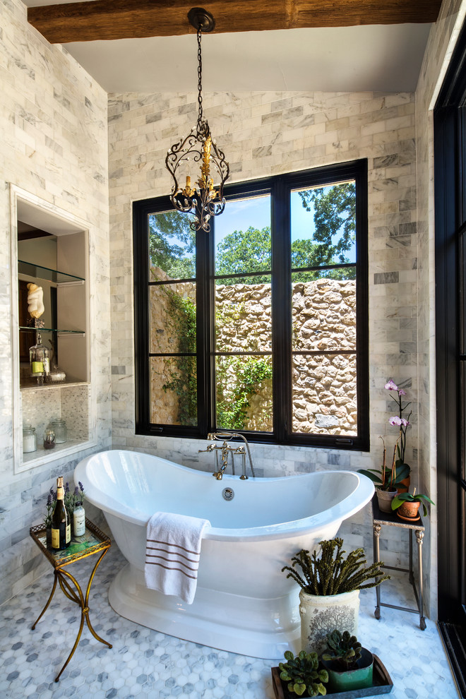 This is an example of a mid-sized country master bathroom in Dallas with raised-panel cabinets, dark wood cabinets, a freestanding tub, an alcove shower, a two-piece toilet, beige tile, stone tile, grey walls, marble floors, an undermount sink and marble benchtops.